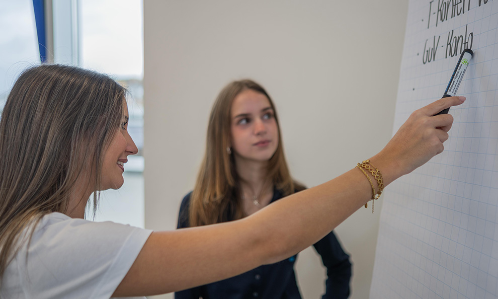 Zwei Personen schauen auf ein Board und besprechen etwas
