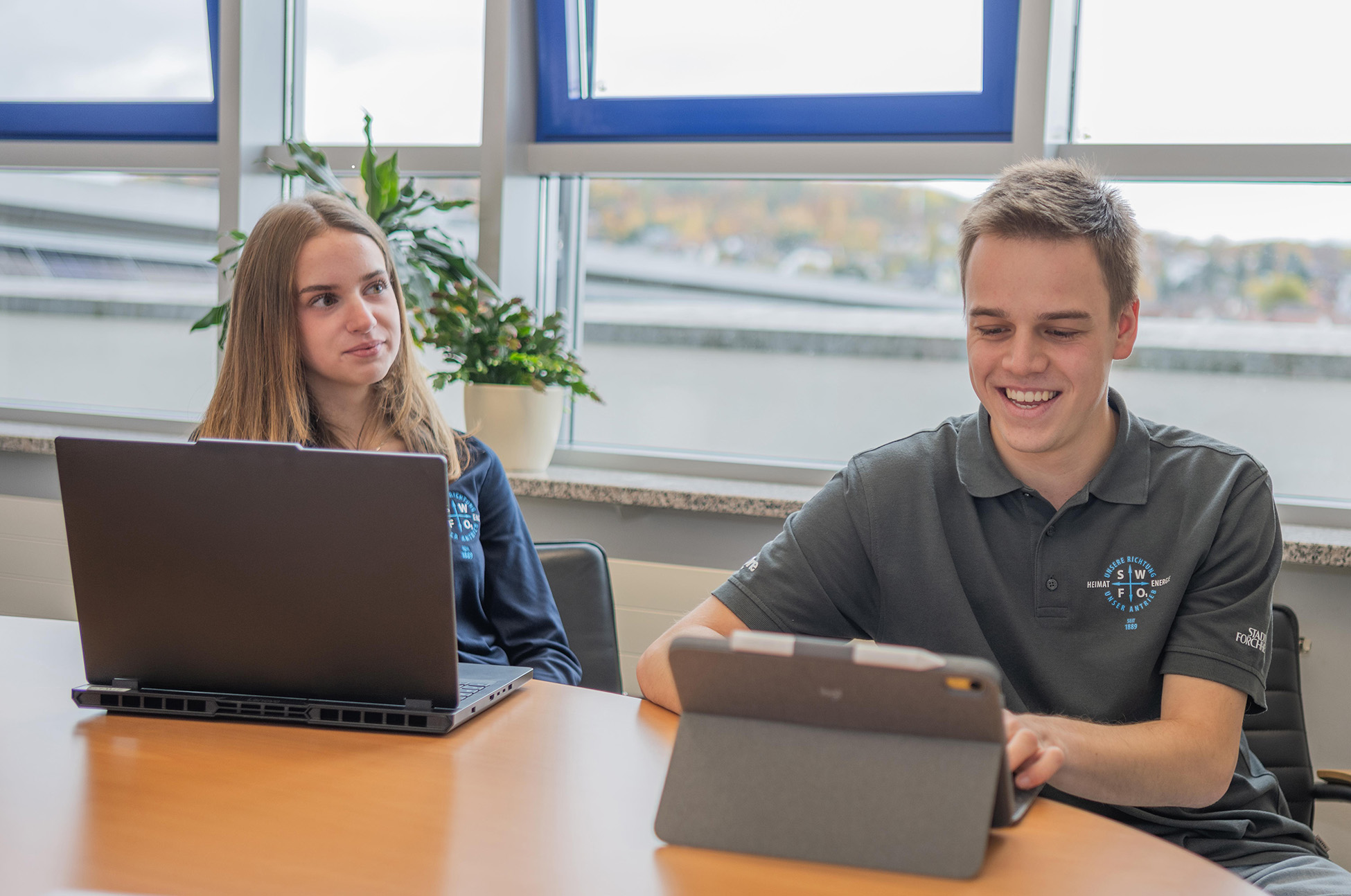 2 Personen arbeiten lächelnd am Laptop